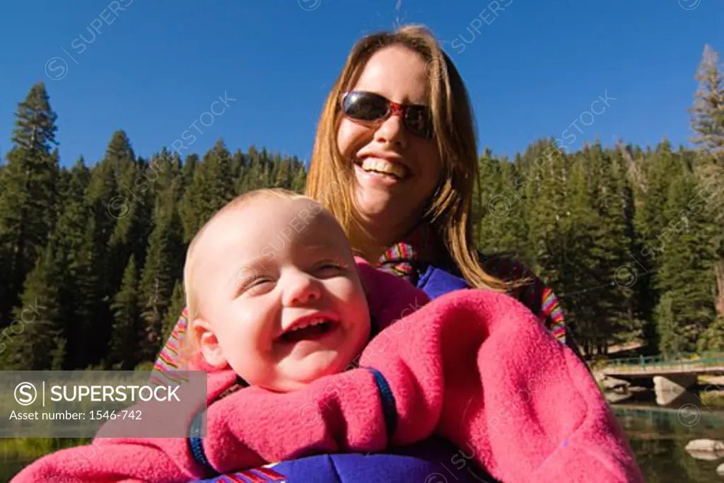 Young woman holding her daughter and laughing, Truckee River, California, USA
