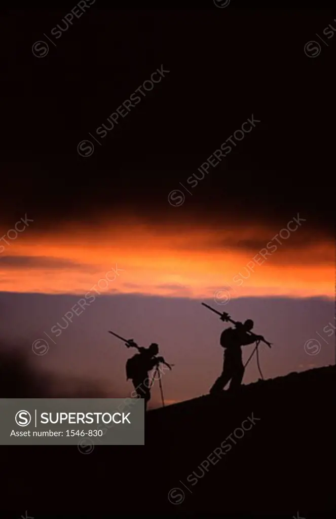 Silhouette of two skiers hiking at sunset after a storm while skiing, Mt Hood, Mt Hood National Park, Oregon, USA