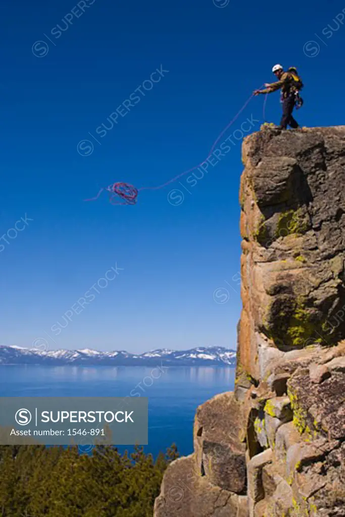 Mountaineer throwing a climbing rope off a cliff, Lake Tahoe, Nevada, USA