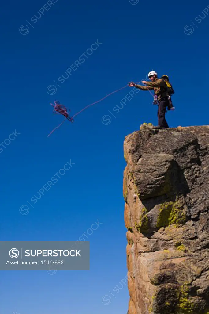 Mountaineer throwing a climbing rope off a cliff, Lake Tahoe, Nevada, USA -  SuperStock