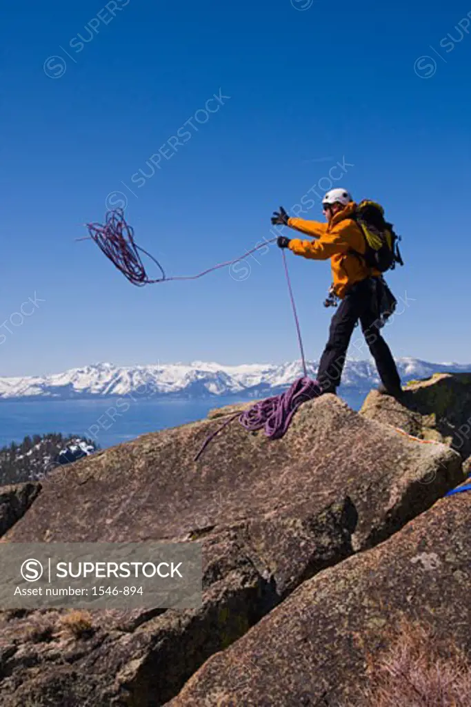Mountaineer throwing a climbing rope off a cliff, Lake Tahoe, Nevada, USA