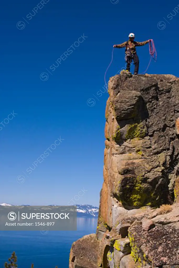 Mountaineer standing on top of a cliff and coiling his climbing rope, Lake Tahoe, Nevada, USA