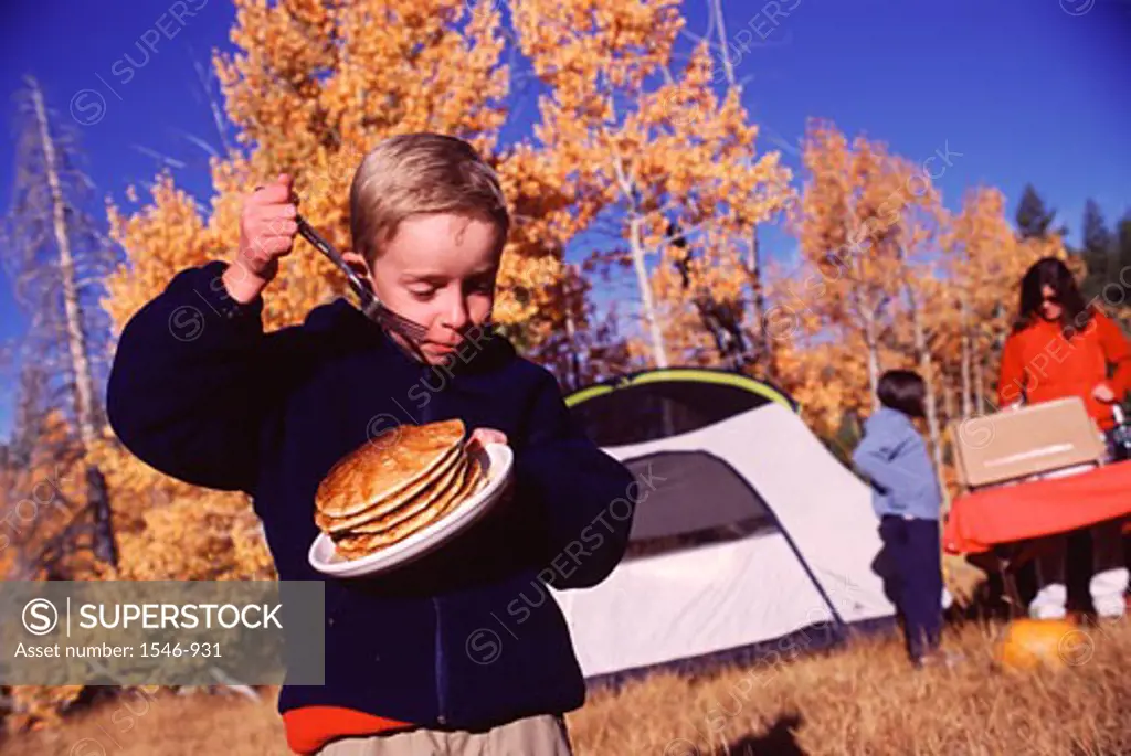 Boy holding a plate of breads and a fork while camping, Truckee, Nevada County, California, USA