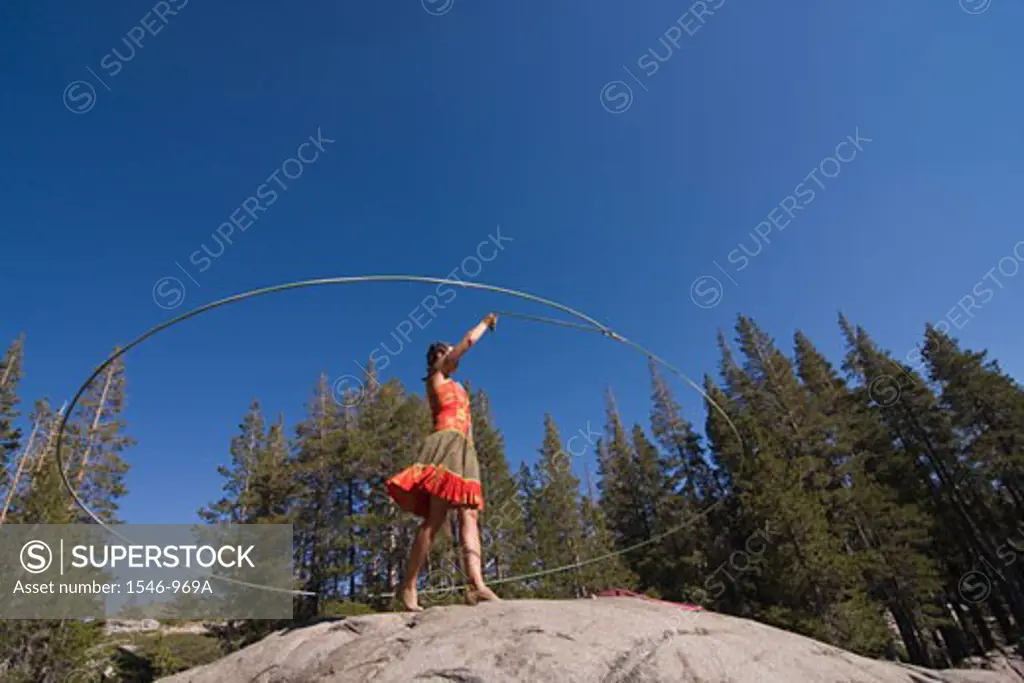 Woman practicing with a lariat in a forest