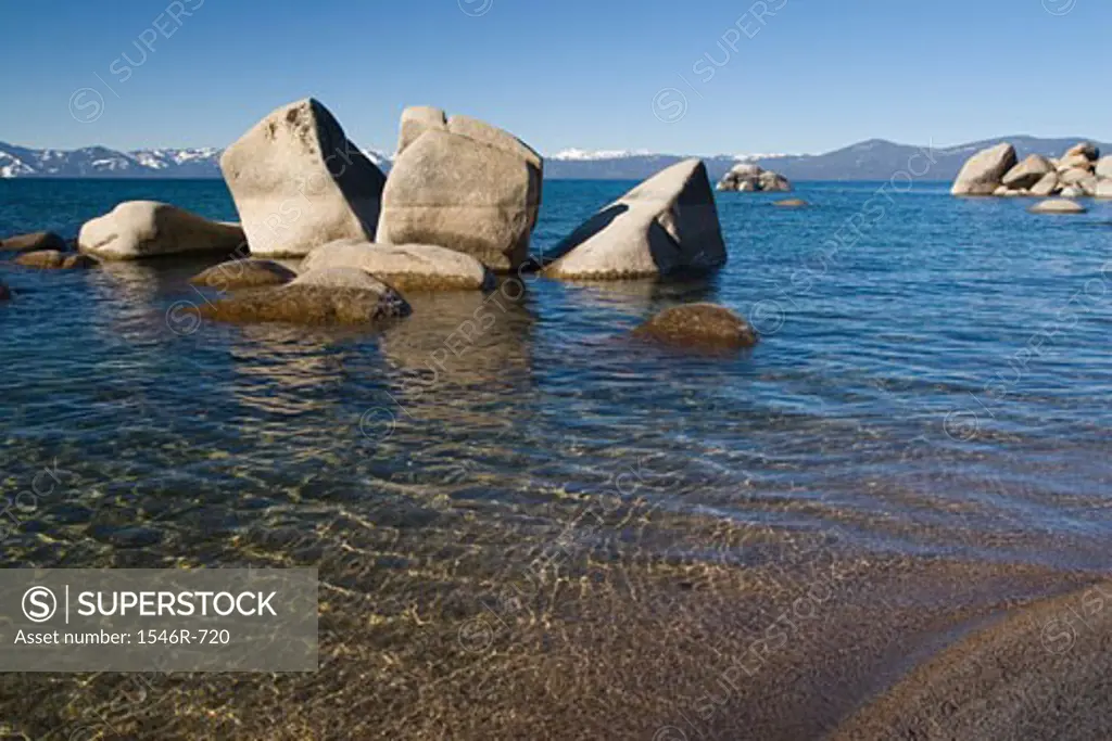 Rock formations in a lake with mountains in the background, Lake Tahoe, Nevada, USA