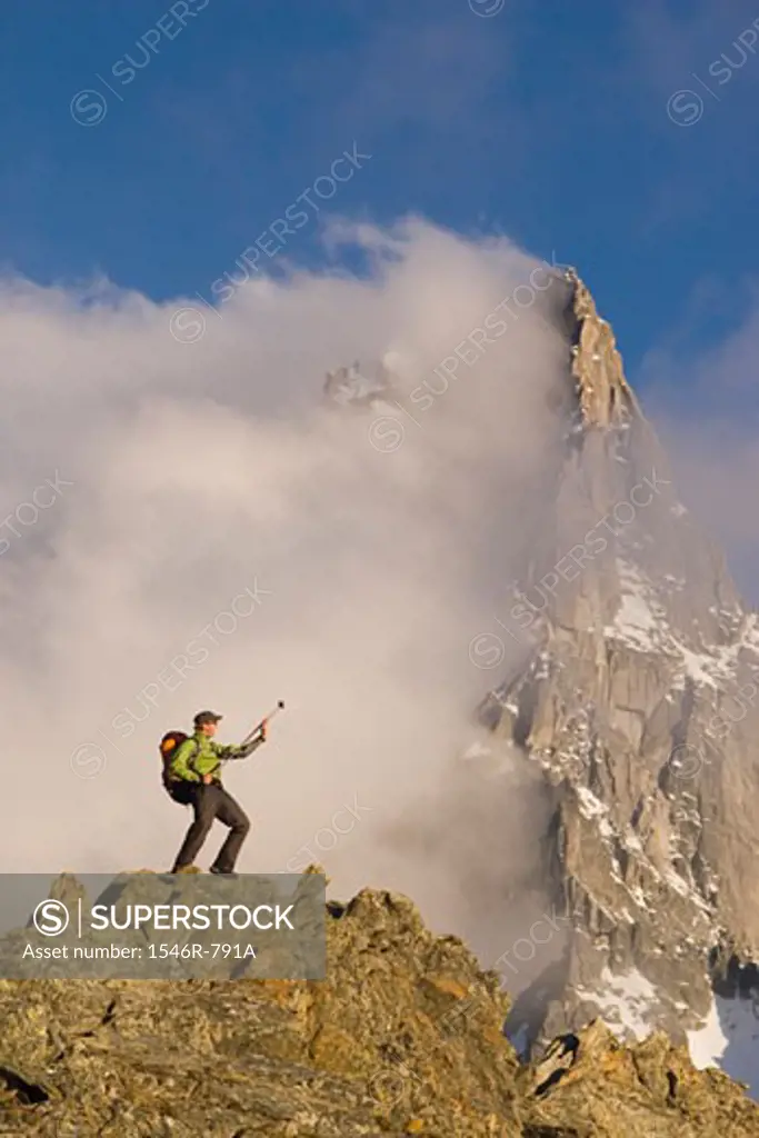 Low angle view of a hiker standing on a rock and playing an air guitar, French Alps, Chamonix, France