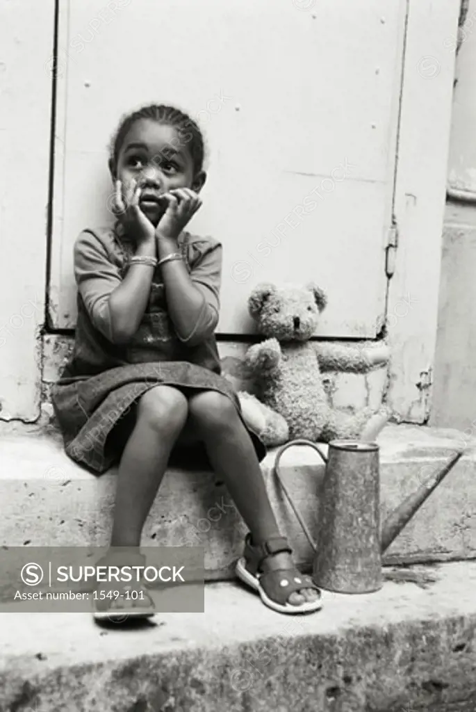 Girl sitting on a doorstep with her hands on her chin