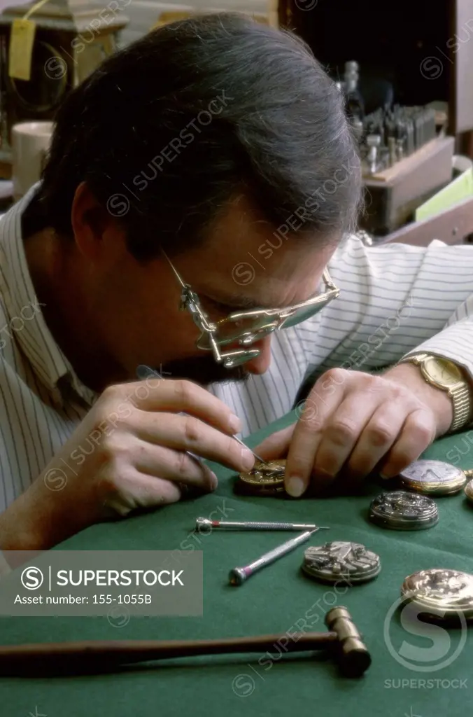 Mature man repairing watches in shop