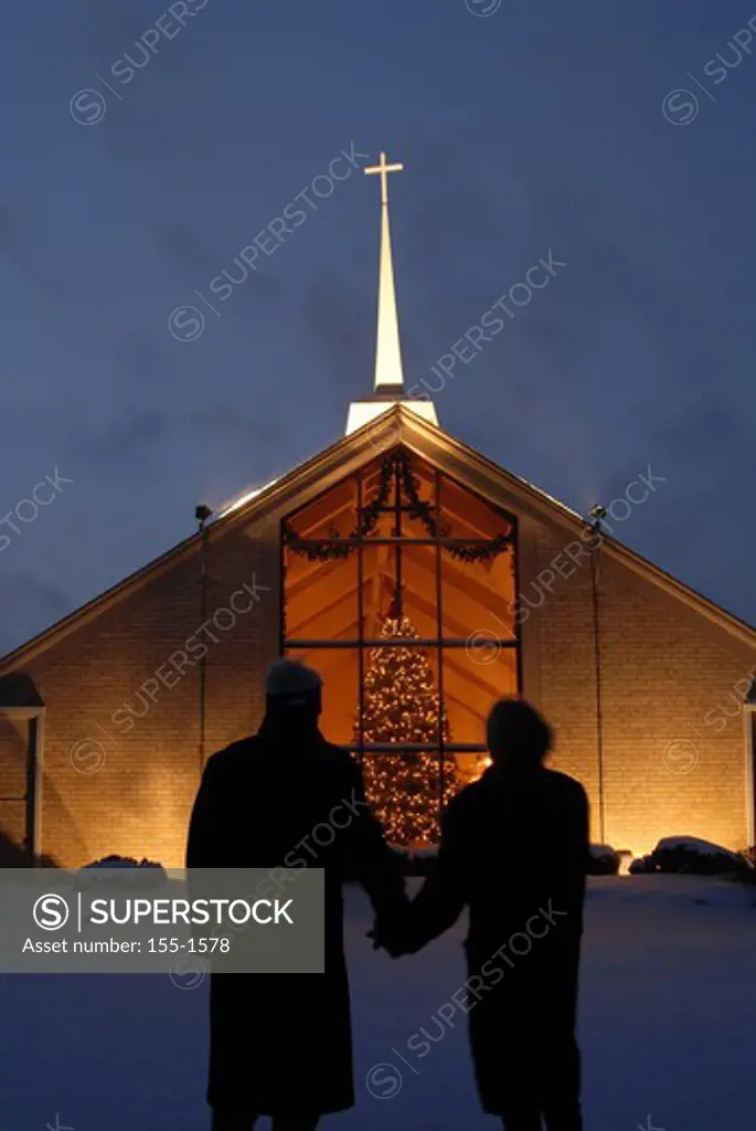 Silhouette of a couple standing in front of a church during Christmas 