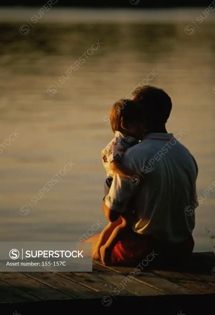 Mid adult man sitting on a pier with his son