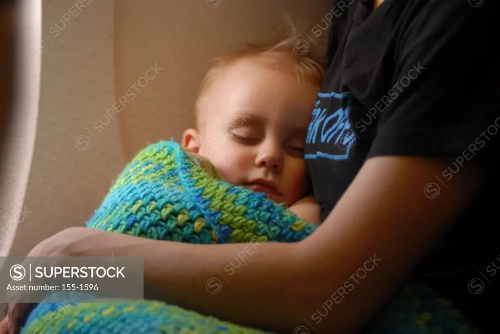 Baby boy sleeping in his mother's arms