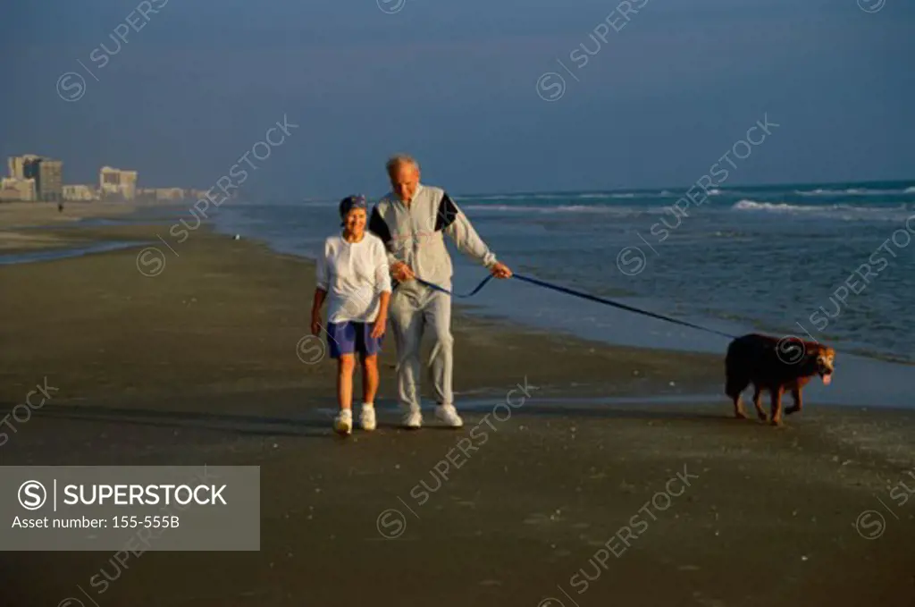 Senior couple walking with dog on the beach
