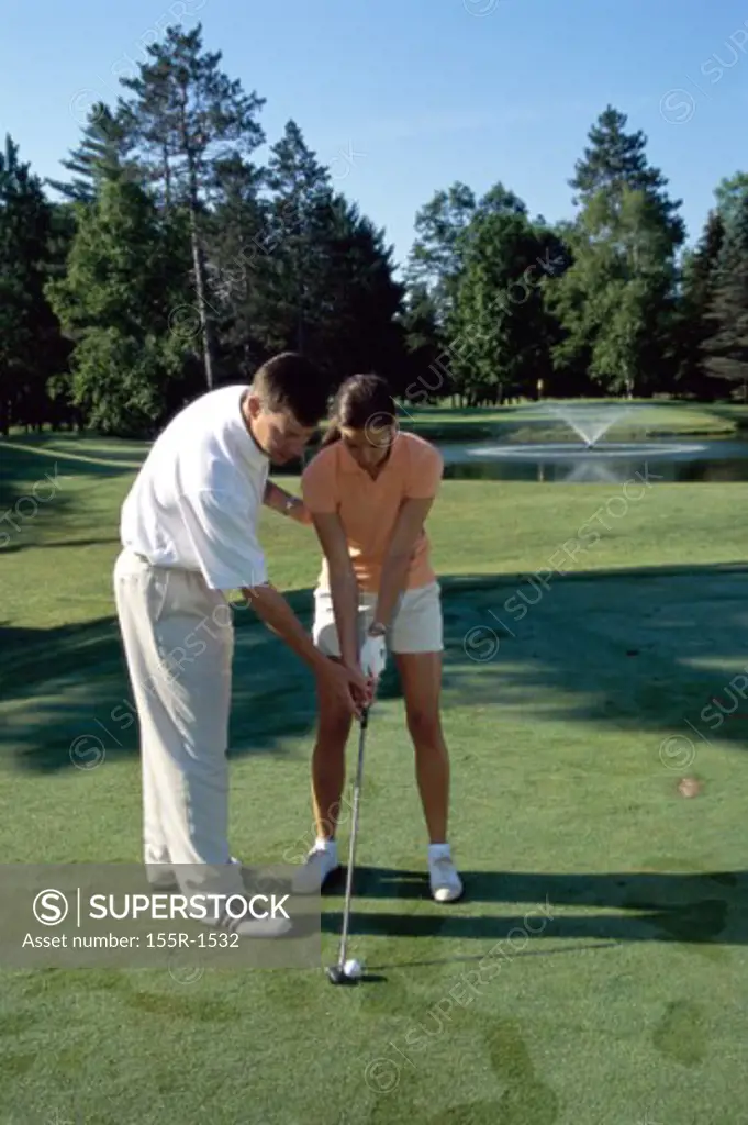 Young man teaching a mid adult woman golf