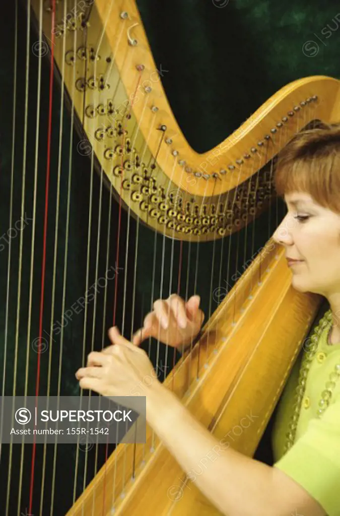 Side profile of a mid adult woman playing the harp
