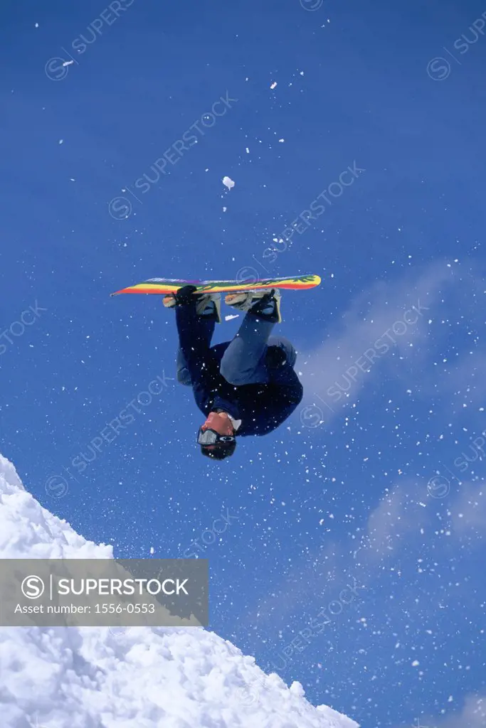 Young adult man performing stunt on snowboard