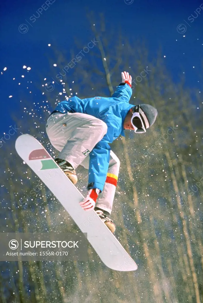 Young adult man performing stunt on snowboard