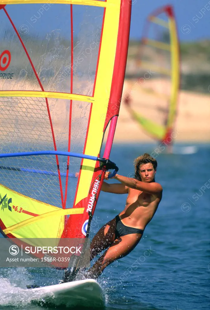 Topless young woman windsurfing