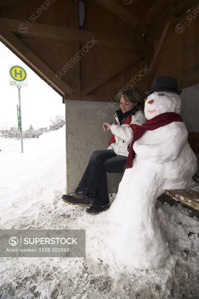 Bus stop, wood bank, snowman, Woman, young, gesture, watch, winters,   20-30 years, blond, winter clothing, sitting, stop, shelters, means of transpor...