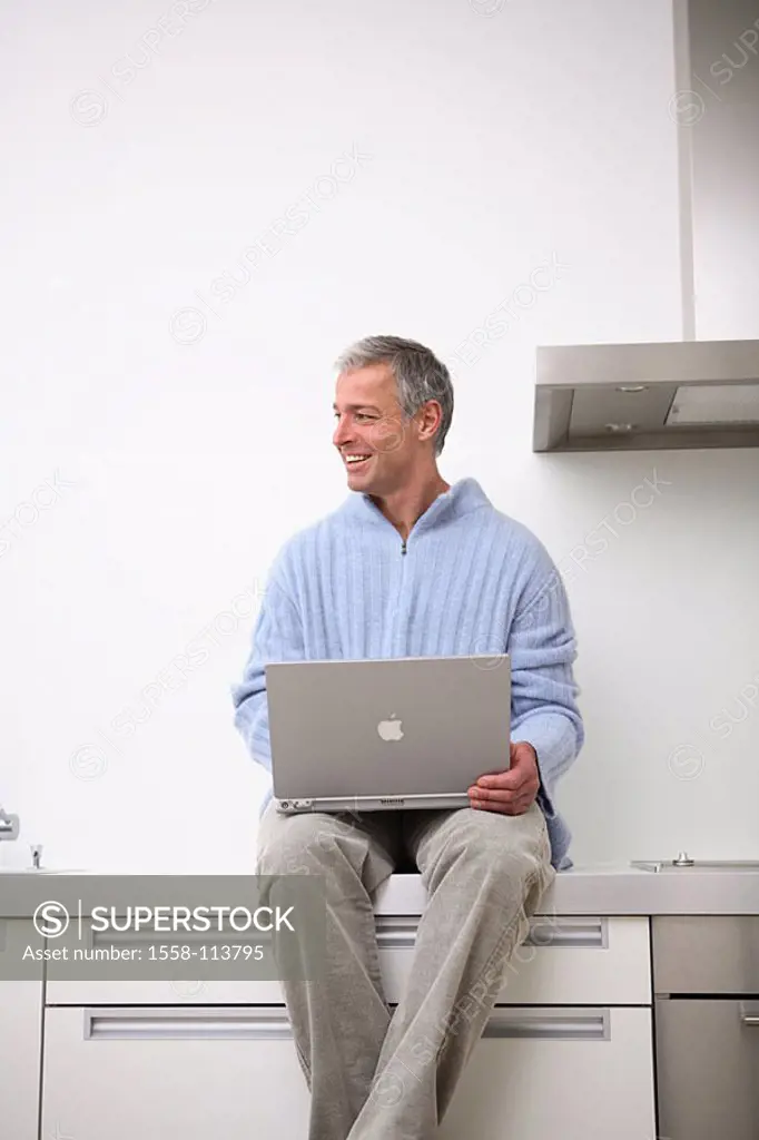 Man, laptop, kitchen-line, sits, no property release, people, 30-40 years, 40-50 years, grey-haired, smiles, cheerfully, nonchalant, casual, leisure t...