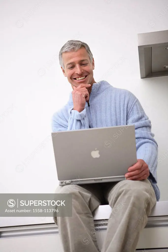 Man, laptop, kitchen-line, sits, no property release, people, 30-40 years, 40-50 years, grey-haired, smiles, cheerfully, nonchalant, casual, leisure t...