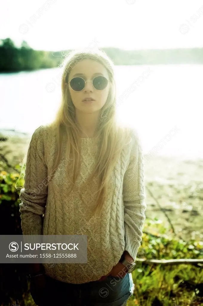 Blonde young woman with sunglasses by the lake,