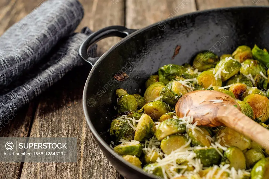 Pan-fried Brussels sprouts in cast-iron frying pan on wooden table