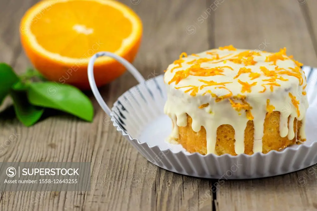 Small orange cake with white icing on wooden table