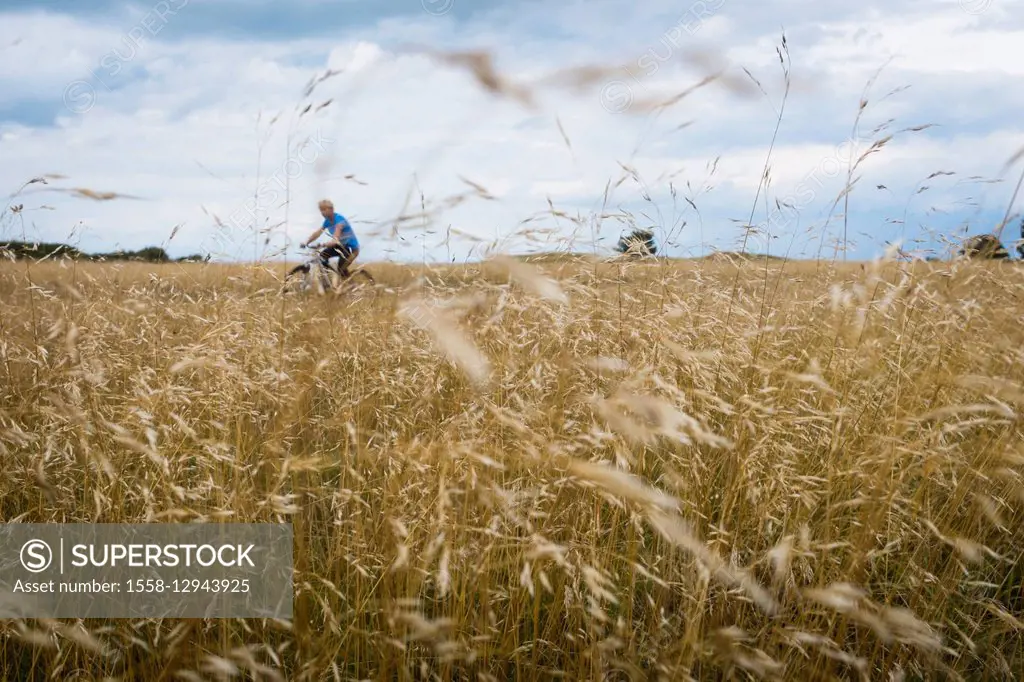 Boy with bicycle in grain field