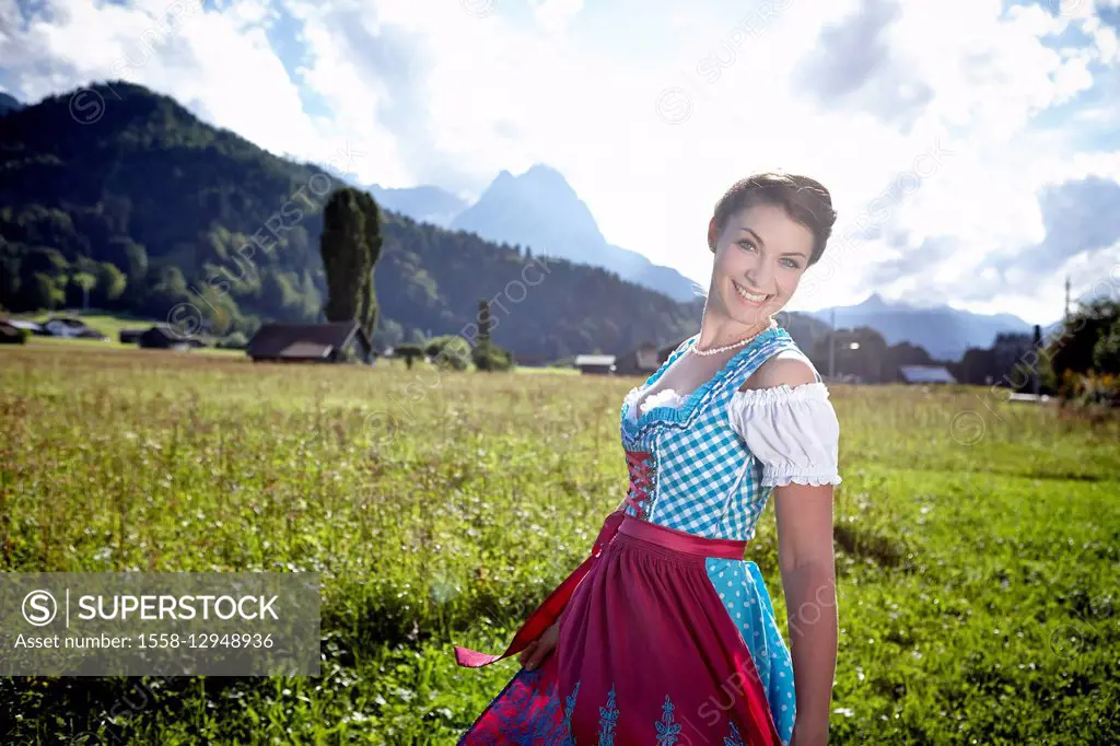 Young woman in dirndl, outdoors, meadow