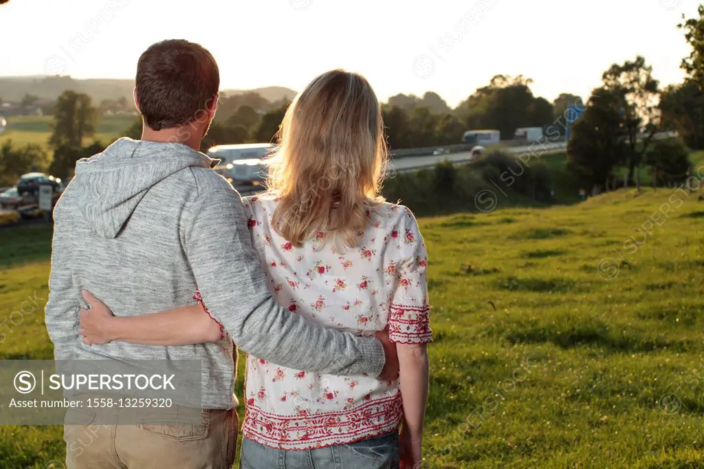 Couple, young, meadow, standing, arm in arm, back view,