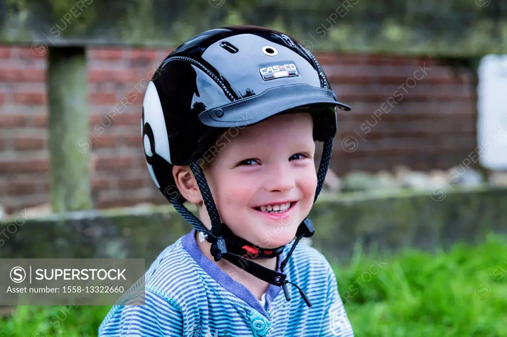 Little boy with bicycle helmet, is grinning into the camera, half portrait,