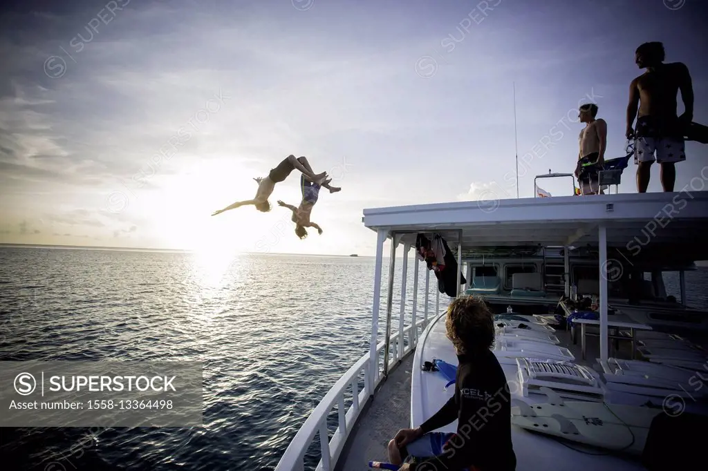 two young men are jumping with backflip from boat