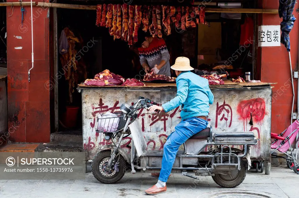Lhasa, Old, Man on moped in front of butcher