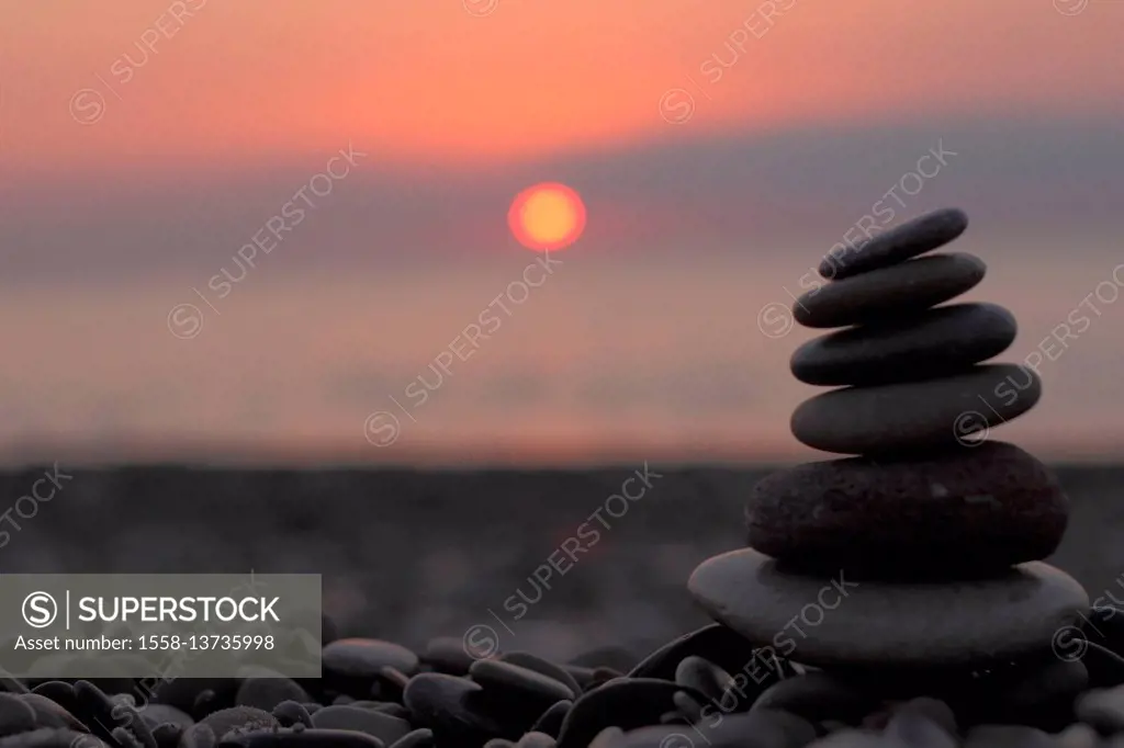 cairn on the beach in front of the rising sun