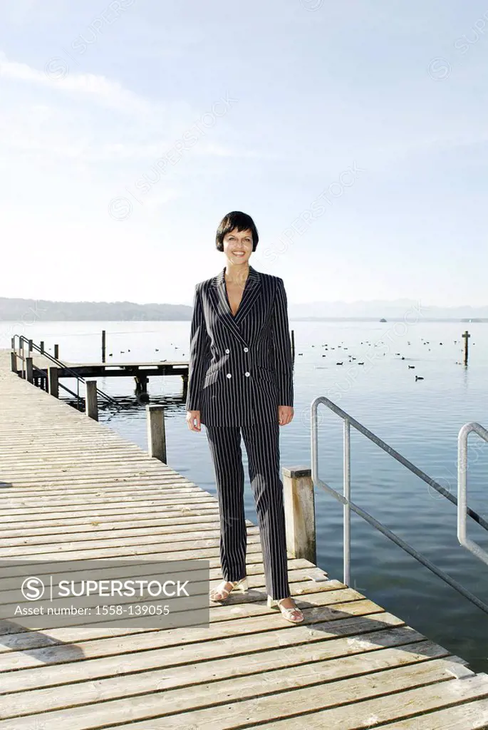 Woman, smiling, stands, bridge, lake, series, people, 30-40 years, brunette, pant suit, businesswoman, leisure time, summer, sunny, outside, full-leng...