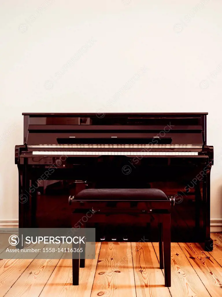 Black piano with a piano stool on a wooden ground in the living room - copy space