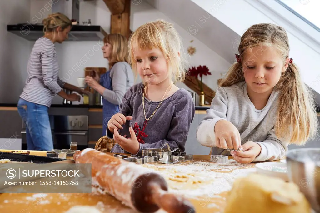 Girls baking christmas cookies, portrait, mother and grandmother in background,