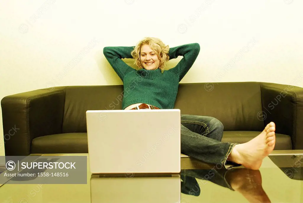 woman, young, blond, sofa, sitting, feet, table, laptop, happily, smile,
