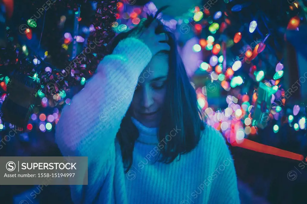 brunette woman moving her hair between Christmas lights