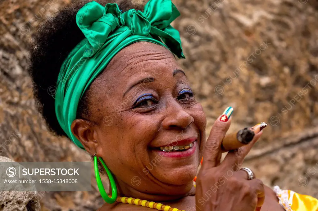 old Cuban woman with green hair ribbon smokes a Havana cigar, Caribbean, Central America, La Habana, Cuba