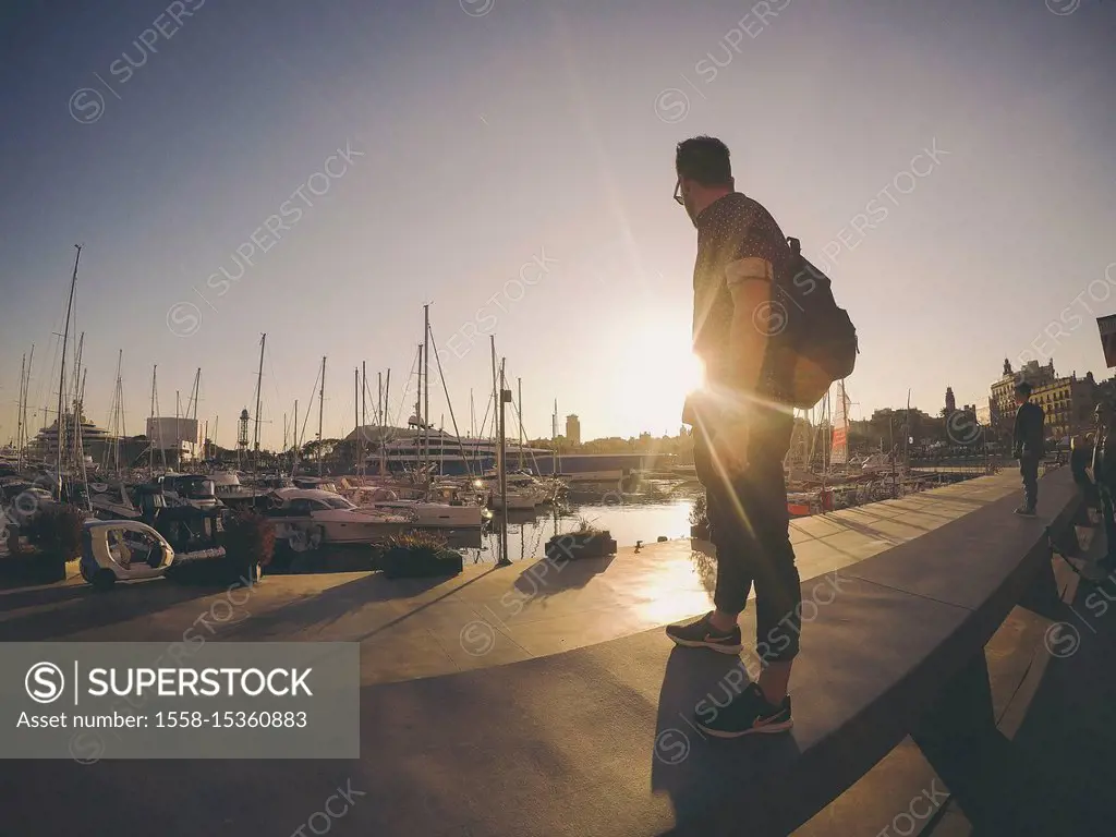 young tourist man staring to the sunset at Barcelona port