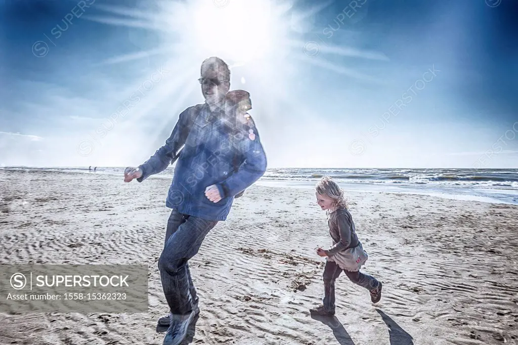 Father and daughter are running on the beach