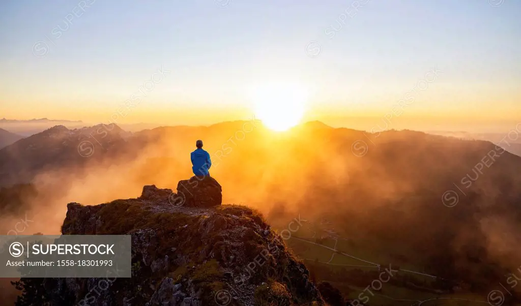 Man enjoys the sunset on the summit of Sorgschrofen near Jungholz. Allgäu Alps, Bavaria, Germany