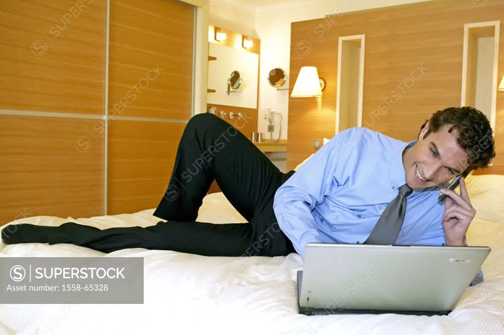 Hotel rooms, man, bed, lie,  Laptop, cell phone, smiling  Series, 30-40 years, businessman, portable phone,  Telecommunication, communication, compute...