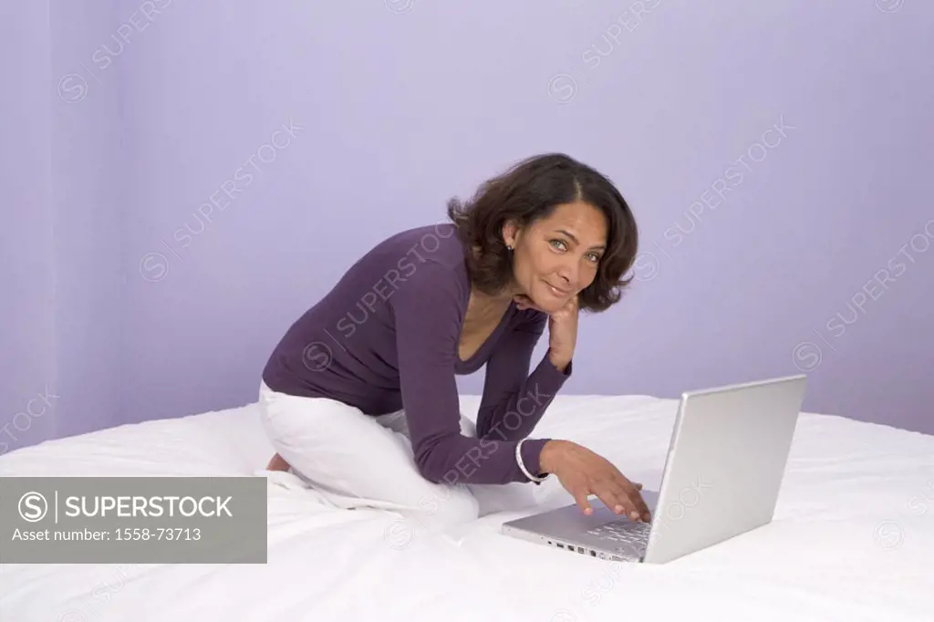 Woman, middle age, laptop,  Bed, kneeling, smiling, gesture   50 years, works at home, computers, joy, cheerfully, pleased, smiling, contentedly, happ...