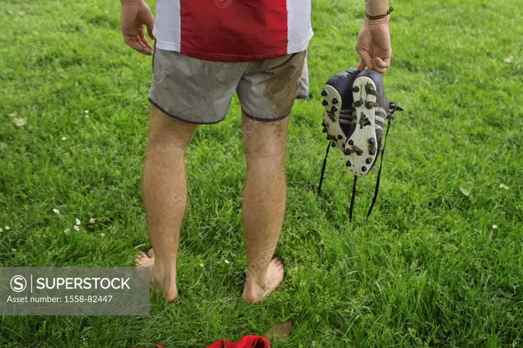 Meadow, man, nakedfoot, stand,  Football shoes, holding, view from behind,  Detail  Soccer players, 20-30 years, legs, pants, shorts, dirty, jersey, r...