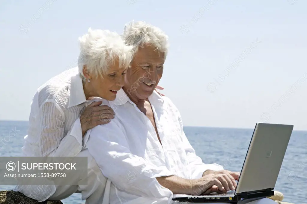 Sea, rock coast, senior couple, laptop,  Data input, happy,   Series, 50-60 years, well Age, seniors couple couple white-haired clothing white, sittin...