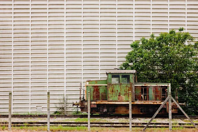 Discarded locomotive in front of industrial facade