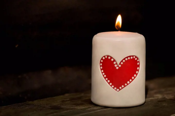 White table candle with red heart and flame