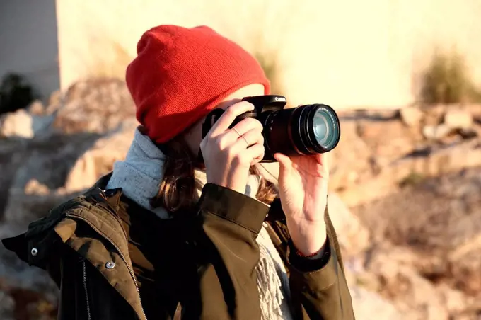 Woman with red beanie photographed with DSLR camera